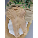 Macacão de Bebê Minimalista com Zíper em tom bege sobre tecidos neutros