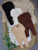 Macacão de Bebê Minimalista com Zíper disponível em várias cores sobre uma superfície neutra